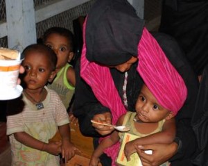 Administration of Plumpy’Doz in a CMAM program, Bangladesh. All watching, one eating (Source: UNHCR  Bangladesh)